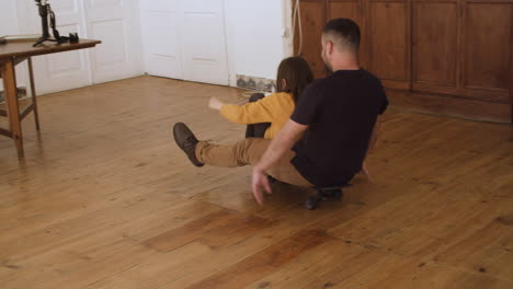 Happy-father-and-daughter-skateboarding-around-apartment.